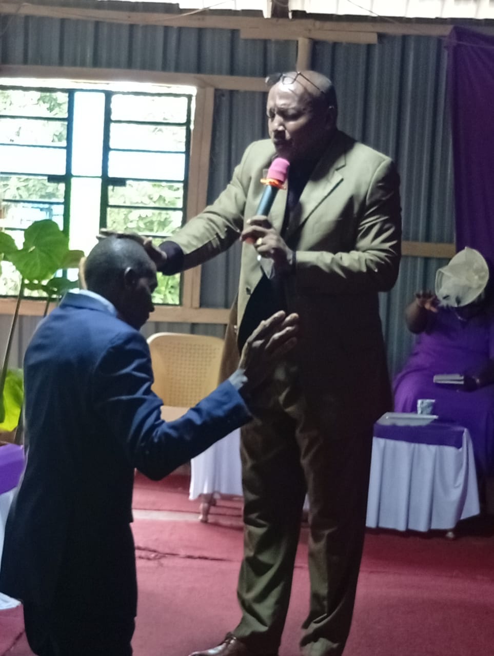 Bishop David Kibali praying with a man at TPC Muiri